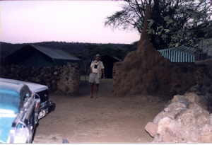 Dr. Harper is dwarfed by the tall termite mound at the entrance to the tent camp